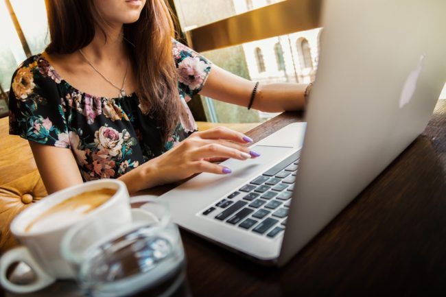 Woman at laptop with coffee next to her